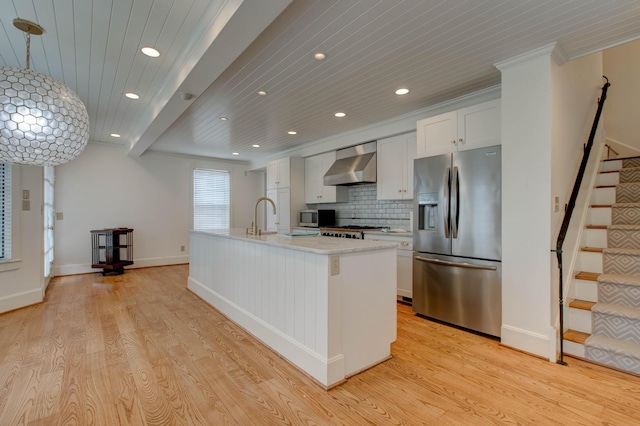 kitchen featuring appliances with stainless steel finishes, wall chimney exhaust hood, a center island with sink, light hardwood / wood-style flooring, and white cabinetry