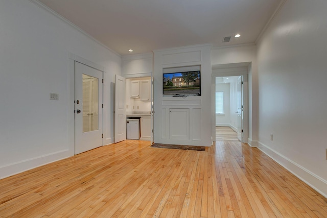 unfurnished living room with crown molding and light wood-type flooring