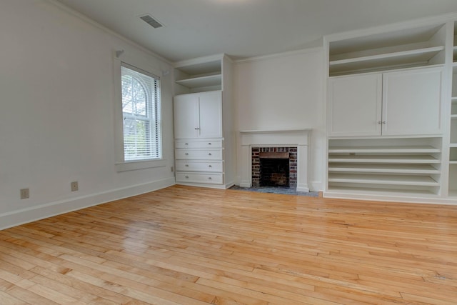 unfurnished living room with built in shelves, a fireplace, ornamental molding, and light hardwood / wood-style flooring