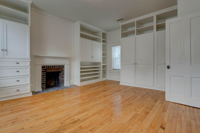 unfurnished living room with built in shelves, light hardwood / wood-style floors, a brick fireplace, and ornamental molding