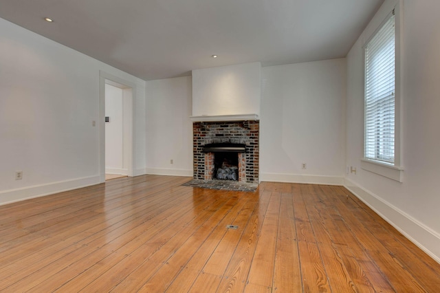 unfurnished living room featuring light wood-type flooring and a brick fireplace