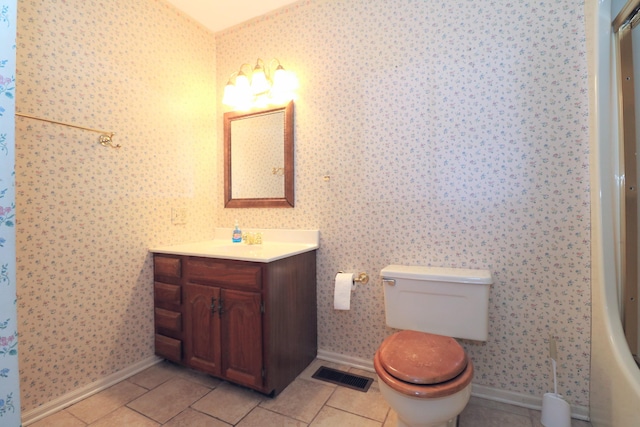 bathroom featuring toilet, wallpapered walls, visible vents, and baseboards