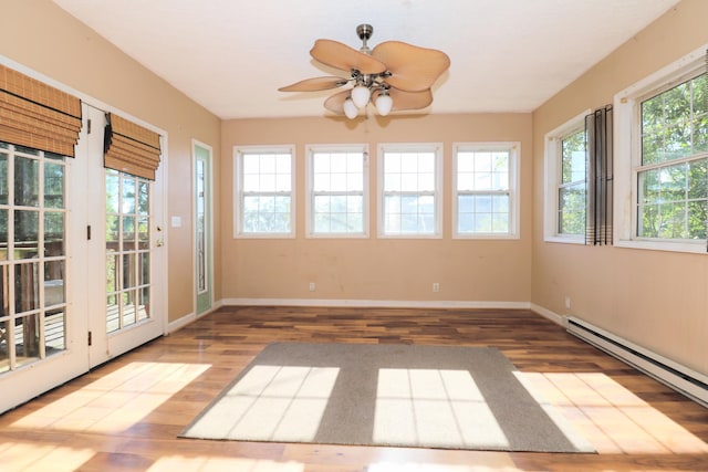 unfurnished sunroom with ceiling fan, a baseboard radiator, and a wealth of natural light