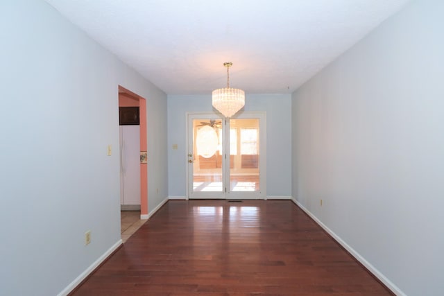 unfurnished dining area featuring dark hardwood / wood-style floors and a chandelier