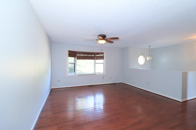 spare room featuring baseboards, a ceiling fan, and dark wood-type flooring