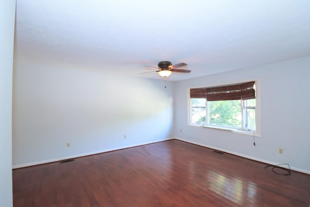 spare room with baseboards, ceiling fan, wood finished floors, and visible vents