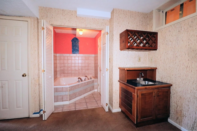 full bath featuring tile patterned flooring, a sink, baseboards, and a bath