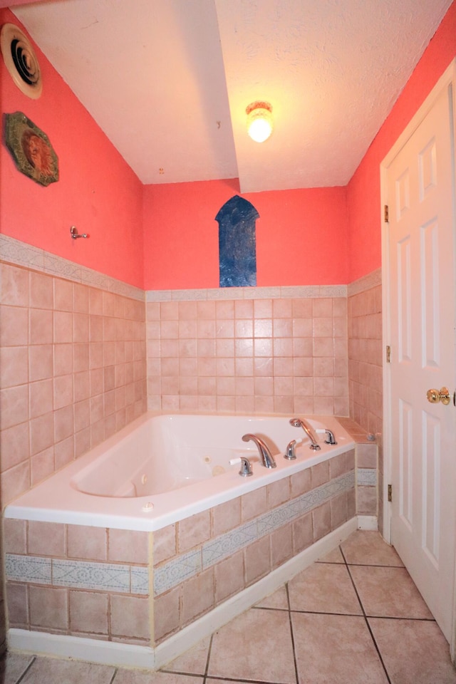 bathroom featuring tile patterned flooring, a textured ceiling, and a relaxing tiled tub