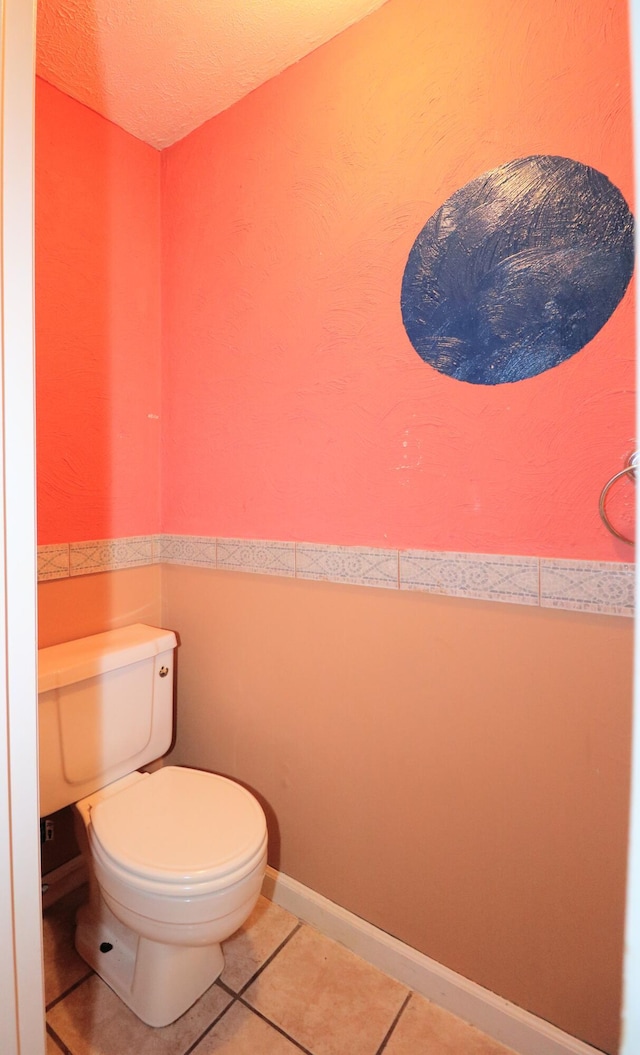 bathroom with toilet, a textured ceiling, and tile patterned flooring
