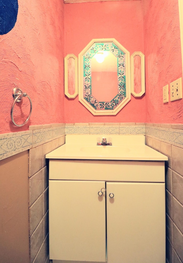 bathroom with vanity, a wainscoted wall, and tile walls