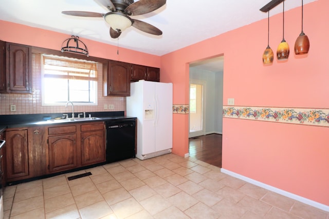 kitchen with decorative backsplash, dark countertops, white refrigerator with ice dispenser, a sink, and black dishwasher