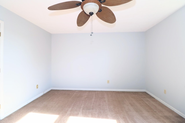 carpeted spare room featuring baseboards and a ceiling fan