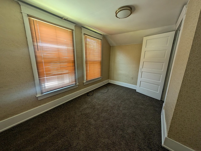 carpeted empty room with vaulted ceiling