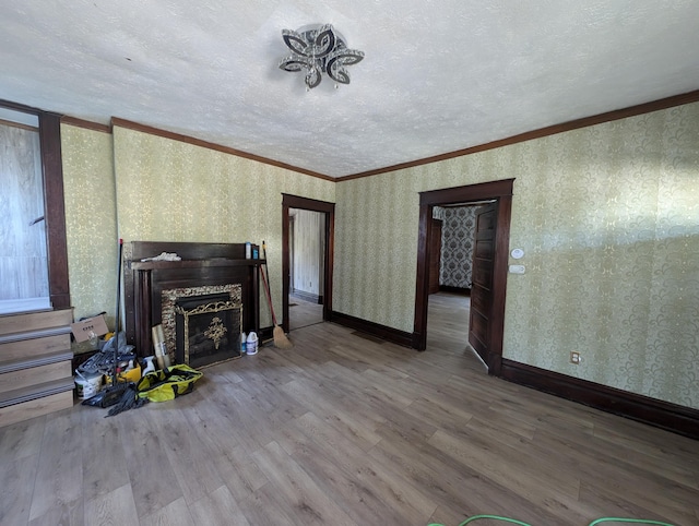 unfurnished living room with a textured ceiling, hardwood / wood-style flooring, and ornamental molding