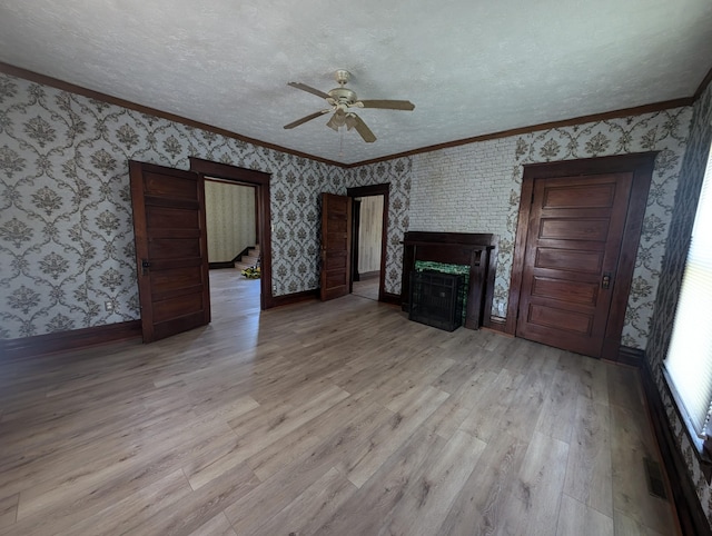 unfurnished living room with ceiling fan, light hardwood / wood-style flooring, a textured ceiling, a fireplace, and ornamental molding