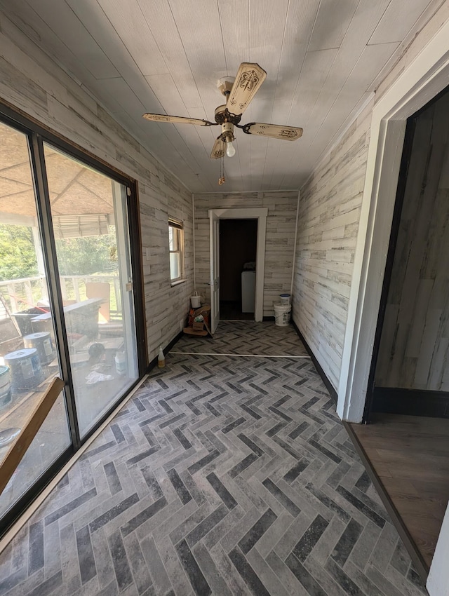 hall with wooden walls, wood ceiling, vaulted ceiling, and washer / dryer