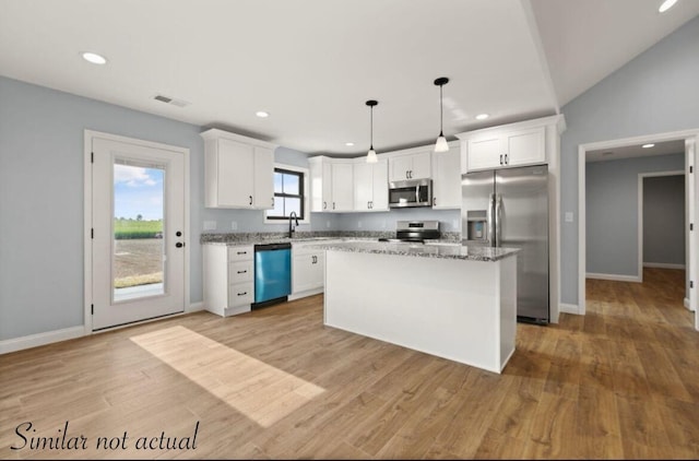 kitchen with stainless steel appliances, a kitchen island, decorative light fixtures, light hardwood / wood-style flooring, and white cabinetry