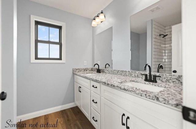 bathroom featuring a shower, wood finished floors, a sink, and baseboards