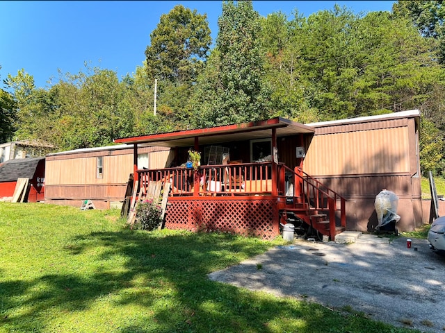 rear view of house featuring a wooden deck and a yard