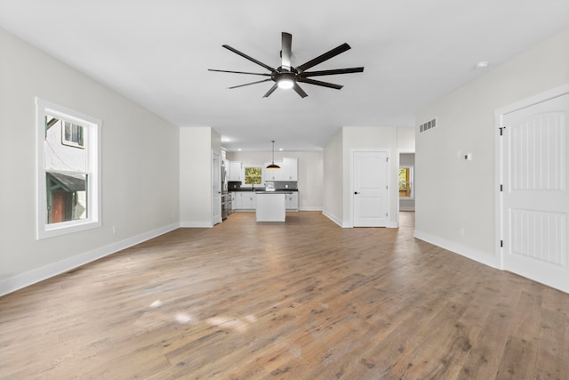 unfurnished living room with ceiling fan, a wealth of natural light, and light hardwood / wood-style floors