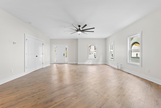 empty room featuring ceiling fan, hardwood / wood-style flooring, and a wealth of natural light