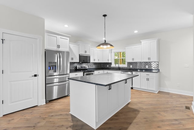 kitchen featuring light hardwood / wood-style floors, decorative light fixtures, appliances with stainless steel finishes, and white cabinetry