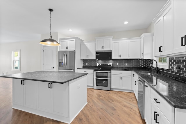 kitchen featuring white cabinets, hanging light fixtures, sink, a kitchen island, and appliances with stainless steel finishes