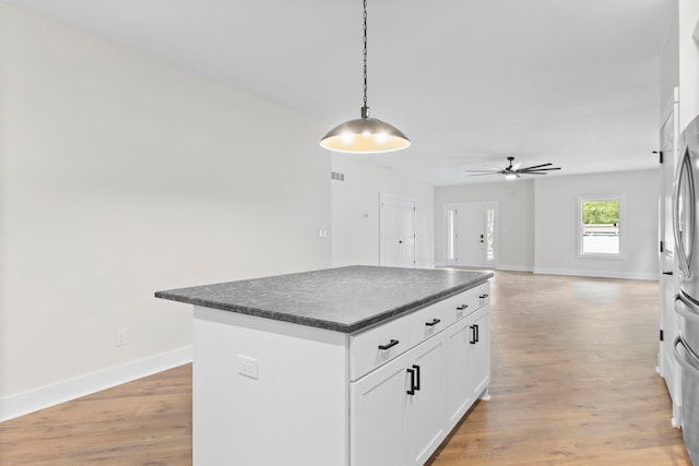 kitchen with ceiling fan, white cabinets, pendant lighting, a kitchen island, and light wood-type flooring