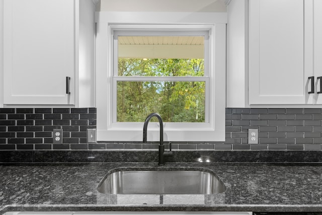 kitchen with white cabinets, dark stone counters, and sink