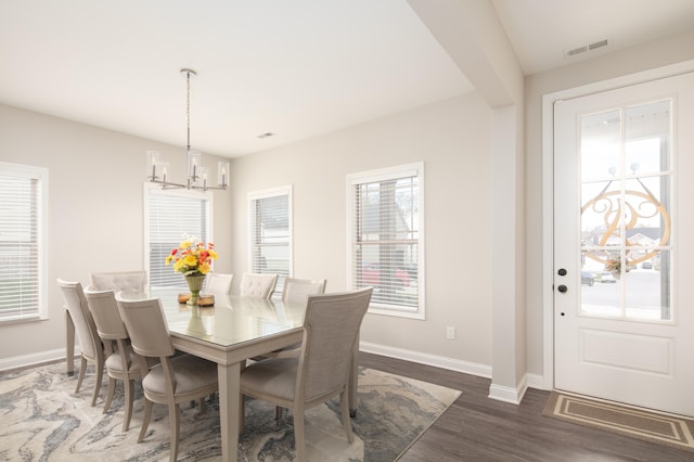 dining room featuring a wealth of natural light, an inviting chandelier, and dark hardwood / wood-style flooring