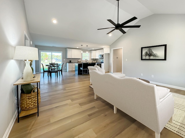 living room featuring sink, vaulted ceiling, light hardwood / wood-style flooring, and ceiling fan