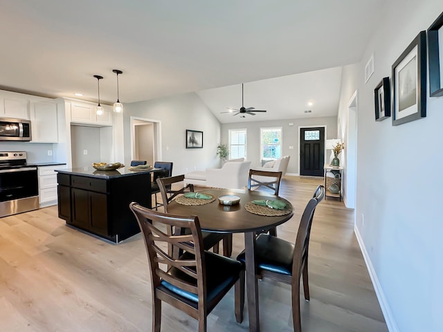 dining space with ceiling fan, vaulted ceiling, and light wood-type flooring