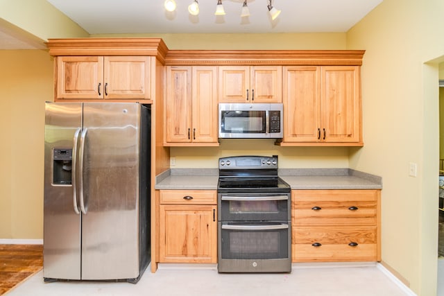 kitchen with stainless steel appliances, light hardwood / wood-style floors, and light brown cabinets