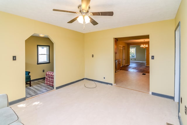 empty room featuring wood-type flooring and ceiling fan with notable chandelier