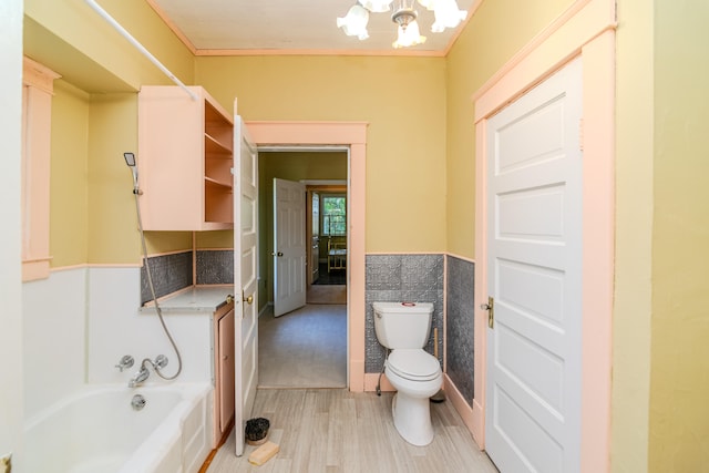 bathroom with hardwood / wood-style flooring, a tub to relax in, tile walls, crown molding, and toilet