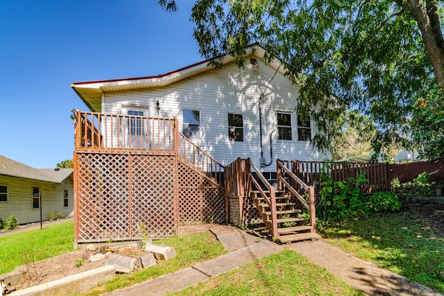 rear view of property with a wooden deck and a lawn