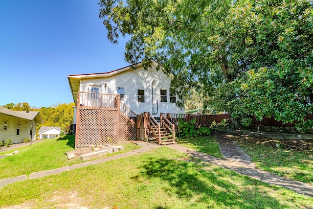 rear view of house featuring a deck and a lawn
