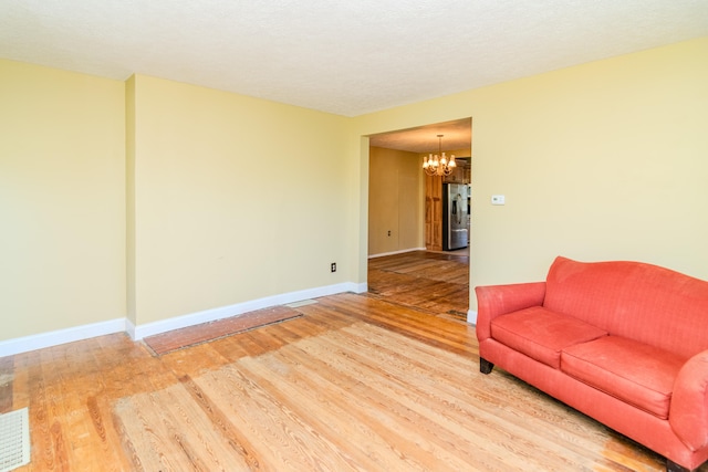 unfurnished living room with hardwood / wood-style flooring, a notable chandelier, and a textured ceiling