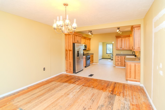 kitchen featuring light hardwood / wood-style flooring, a notable chandelier, sink, hanging light fixtures, and appliances with stainless steel finishes