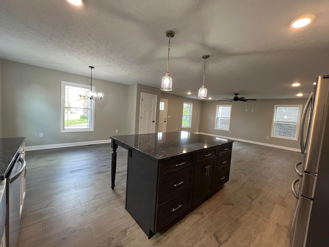 kitchen featuring dark brown cabinetry, hanging light fixtures, stainless steel appliances, dark hardwood / wood-style floors, and ceiling fan with notable chandelier