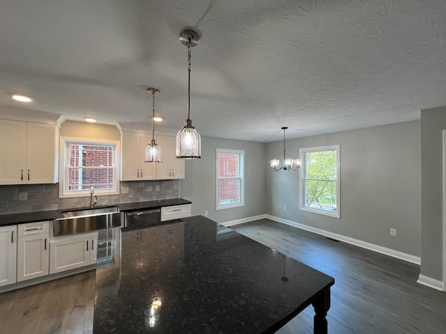 kitchen featuring white cabinets, decorative light fixtures, dark stone counters, and sink