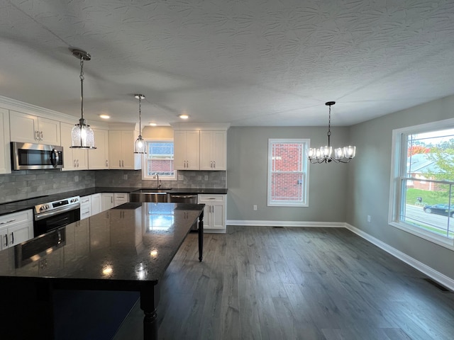 kitchen featuring stainless steel appliances, sink, dark stone countertops, white cabinets, and dark hardwood / wood-style floors