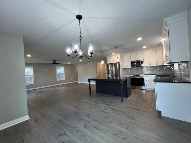 kitchen featuring a center island, dark wood-type flooring, decorative light fixtures, white cabinetry, and stainless steel appliances