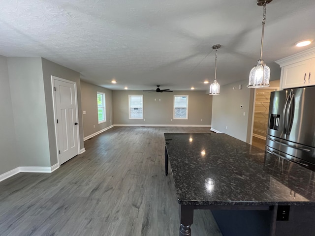 kitchen with white cabinetry, ceiling fan, hanging light fixtures, dark hardwood / wood-style floors, and dark stone countertops