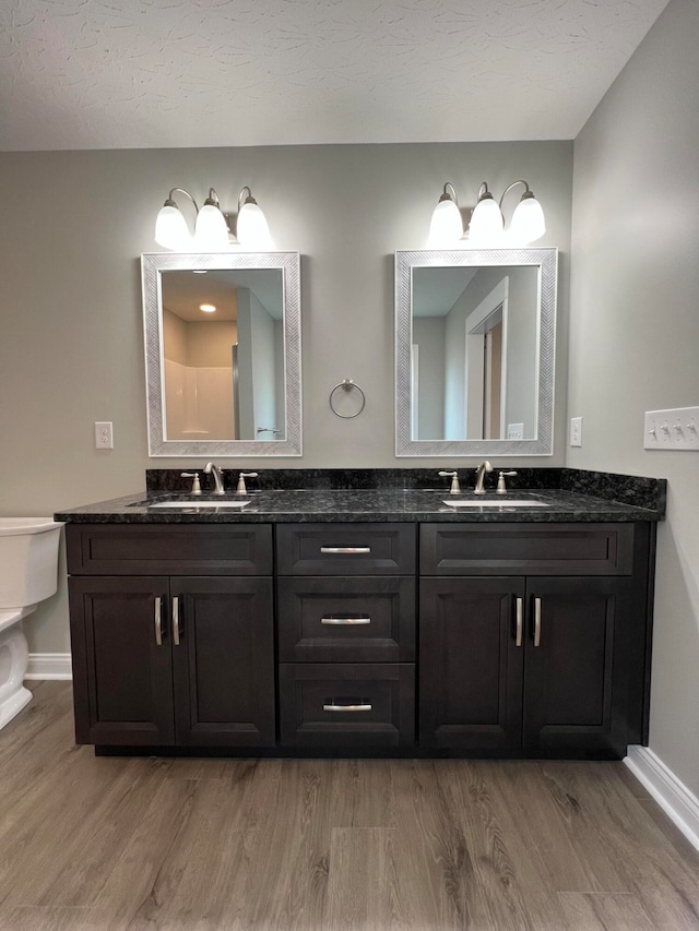 bathroom with hardwood / wood-style floors, vanity, a textured ceiling, and toilet