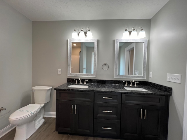 bathroom featuring toilet, vanity, a textured ceiling, and hardwood / wood-style flooring