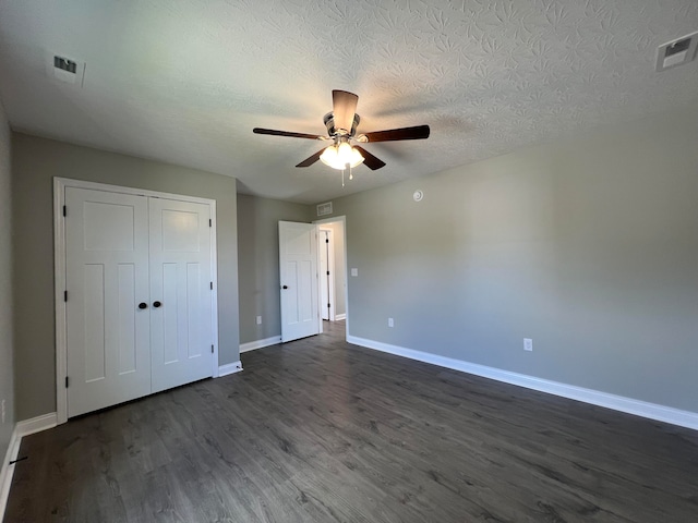 unfurnished bedroom with a closet, a textured ceiling, dark hardwood / wood-style floors, and ceiling fan