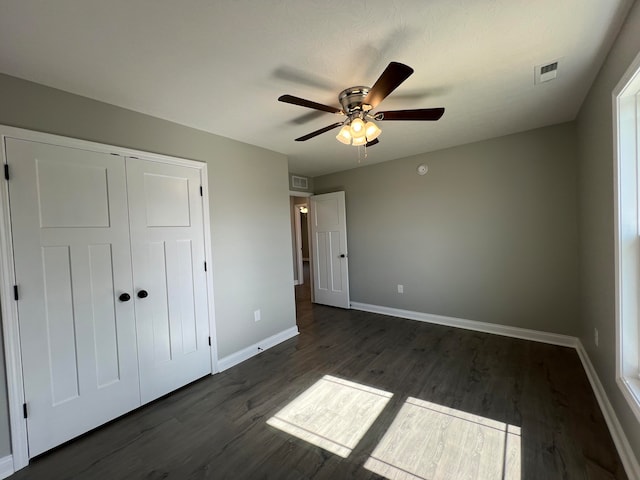 unfurnished bedroom with ceiling fan, dark hardwood / wood-style floors, and a closet