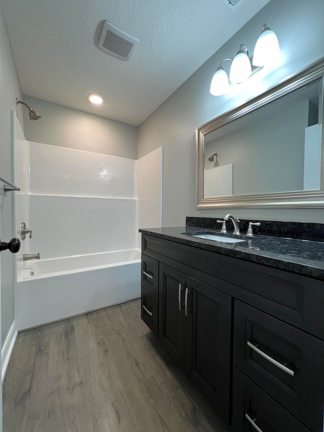 bathroom with shower / washtub combination, vanity, a textured ceiling, and hardwood / wood-style flooring