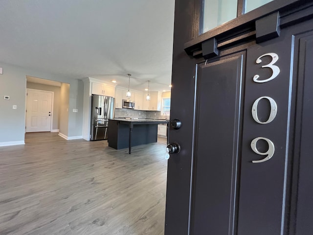 kitchen featuring pendant lighting, a center island, a kitchen breakfast bar, appliances with stainless steel finishes, and white cabinetry